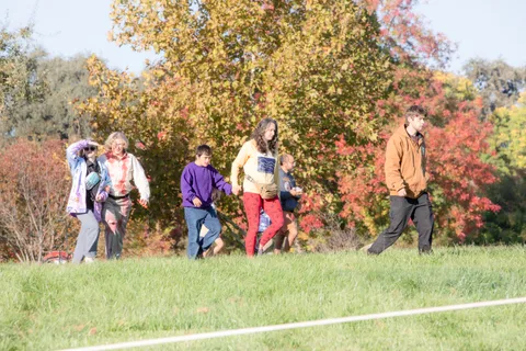A group of five or six, including kids in colorful clothes, walks across the field.