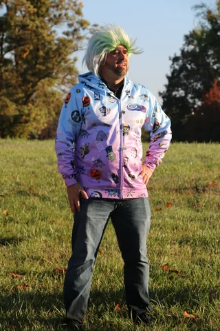 A man in a patterned hoodie stands alone on the lawn.