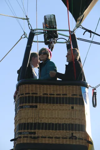 Two riders stand together in the basket looking out.