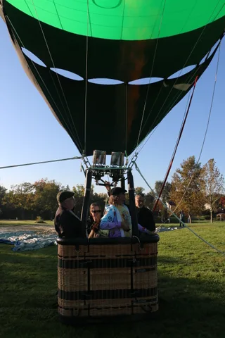 The balloon and basket are silhouetted from below against the morning sky.