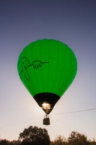 The green balloon glows as morning sun shines straight through the envelope.