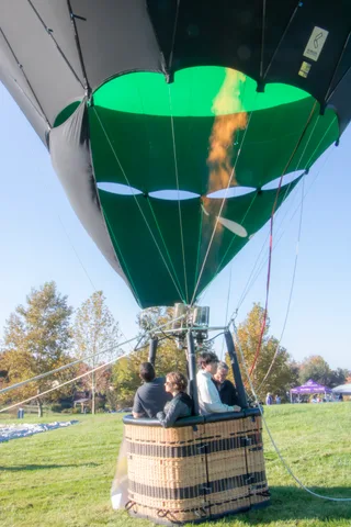 The balloon rises tall in frame with the basket and its riders small at the bottom.