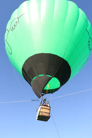 The balloon floats against the sky with the basket small below.
