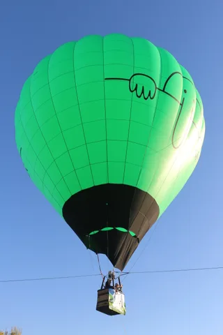 The balloon basket hangs below the envelope against blue sky.
