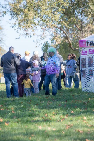 A crowd of guests in costumes mingle and exchange items in the field.