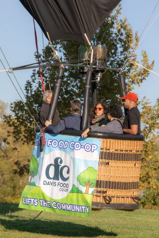 Three adults including a woman in sunglasses stand together in the basket.