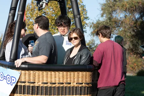 Four young adults lean against the basket edge chatting in good light.
