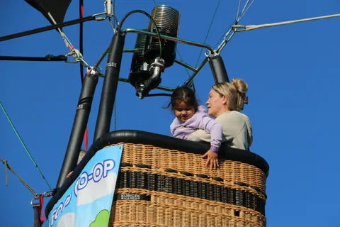 A mother holds a small child up to see over the basket rim.