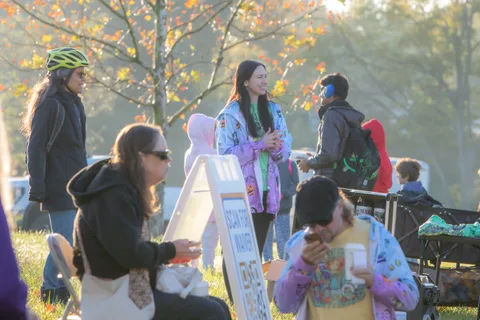 A group including a child stands near a sign on an easel in the grass.