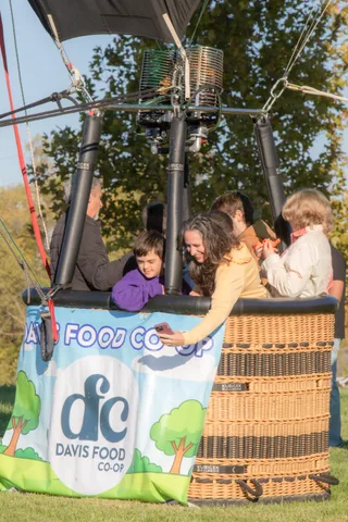 A close group of five or six guests gathers beside the basket.