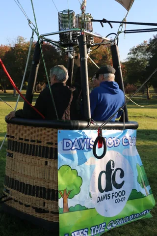 The Davis Food Co-op banner is visible on the balloon basket as a rider looks up.