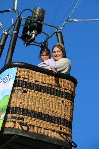 The mother and daughter continue waving from the basket.