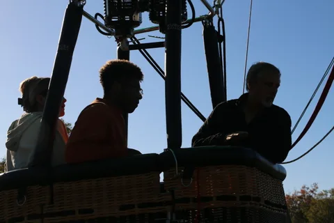 Riders sit in silhouette against the bright balloon fabric.