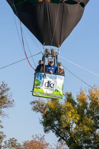The balloon basket rises past its Davis Food Co-op banner.