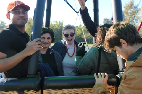 Two women laugh together in the basket as a man looks on smiling.