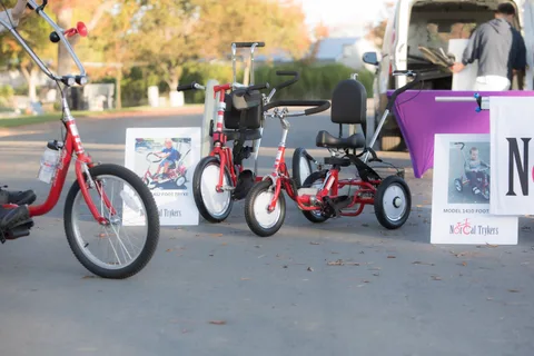 Two adaptive trikes are parked beside a NorCal Trykers sign.
