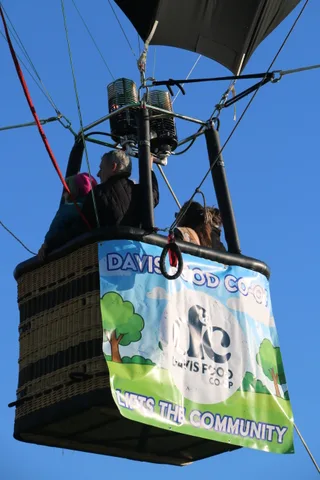 The Davis Food Co-op Lifts the Community banner hangs clearly on the balloon basket.