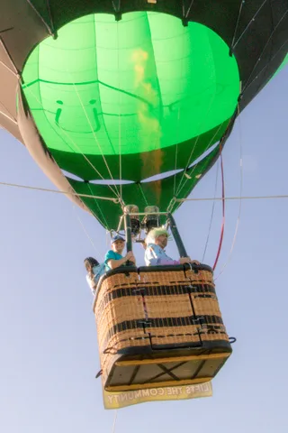 A close view of green balloon fabric glowing where the burner flame lights it from inside.