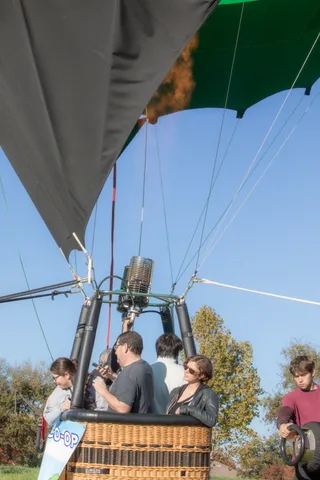 The burner mechanism dominates the frame above three riders in the basket.