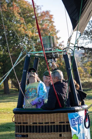 Riders smile together inside the hot air balloon basket.
