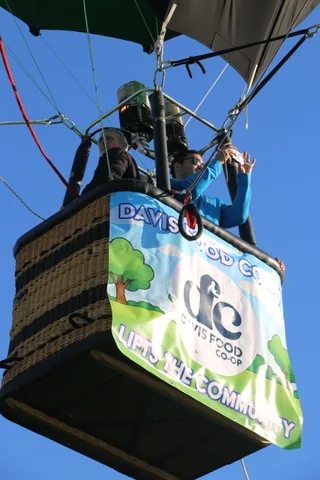 A rider stands beside the Davis Food Co-op banner on the basket.