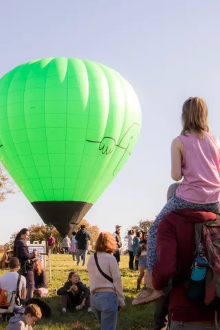 The green balloon rises above a crowd gathered at the community park event.
