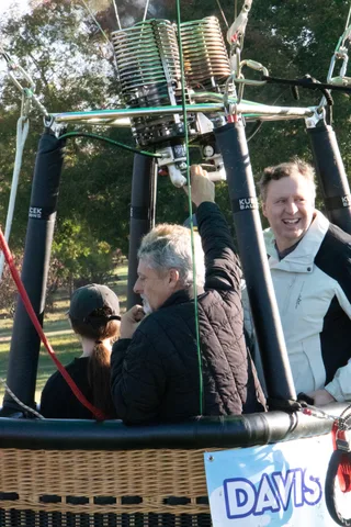 A girl with a braid stands with an older man and others near the grounded basket.