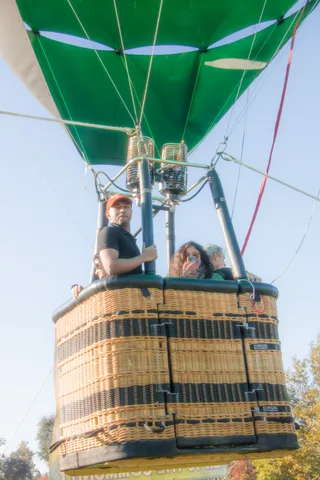 A man in a cap and sunglasses stands with a woman at the edge of the basket.