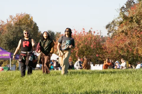 Three costumed guests in zombie makeup stand near a demo tent.