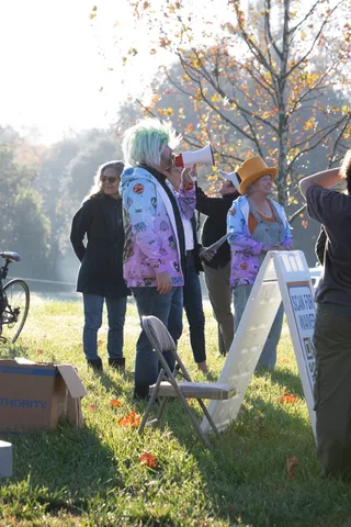 People stand near a folding sign and cardboard box beside the path.