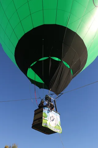 The hot air balloon floats small and distant against a wide blue sky.