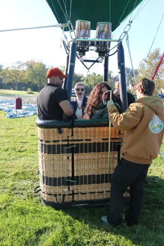 A group gathers near the burner before the balloon lifts off.