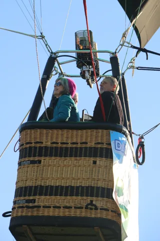 Riders wait in the basket as the co-op banner edge shows at frame right.