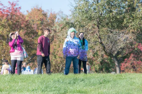 A small group stands scattered across the grass field in the distance.