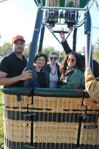 A young man in a red cap smiles broadly with the group in the basket.