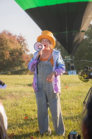A person in a full patchwork scarecrow-style costume stands in the grass.