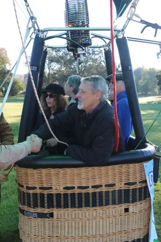 A small group looks up at the burner and rigging inside the basket.