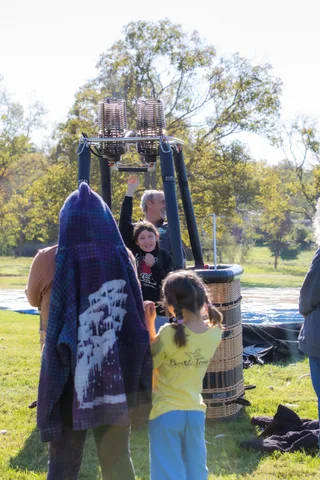 A family wrapped in a blanket watches the morning balloon activity.
