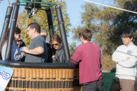 Several riders crowd close together at the edge of the basket.