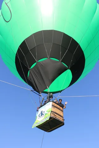The hot air balloon rises with its Davis Food Co-op banner basket against blue sky.