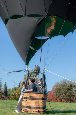 Three riders stand together in the basket in flight.