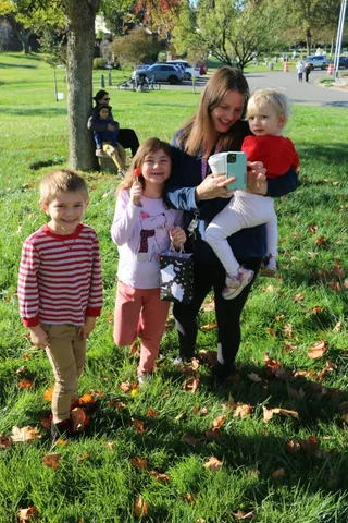 A boy and two women pose together with a young child on the grass.
