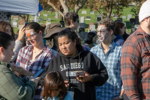 A crowd in zombie face paint and costumes gathers in the cemetery for the festival.