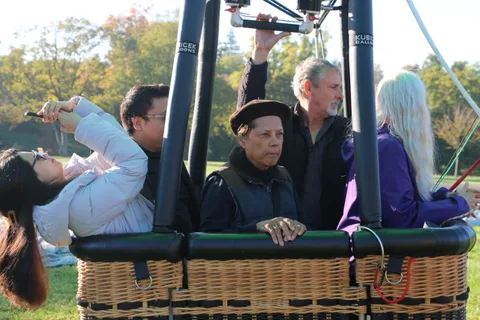A small crowd gathers near the basket after the balloon lands.