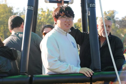 A teenager in a white hoodie stands with the group in the basket.