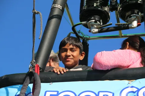 Two children smile together inside the hot air balloon basket.
