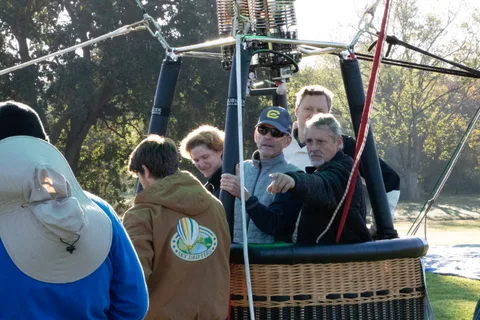 A boy in a cap stands with a small group of men near the grounded basket.