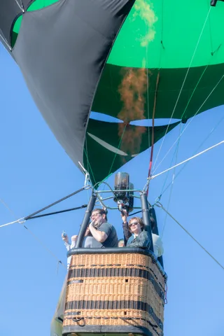 A man photographs the view from the basket while another rider looks on.