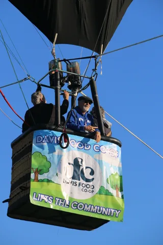 Riders sit in the basket with the Davis Food Co-op banner below them.