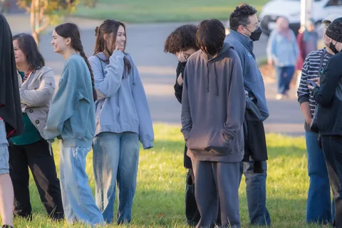 A small group chats together in the grass field.
